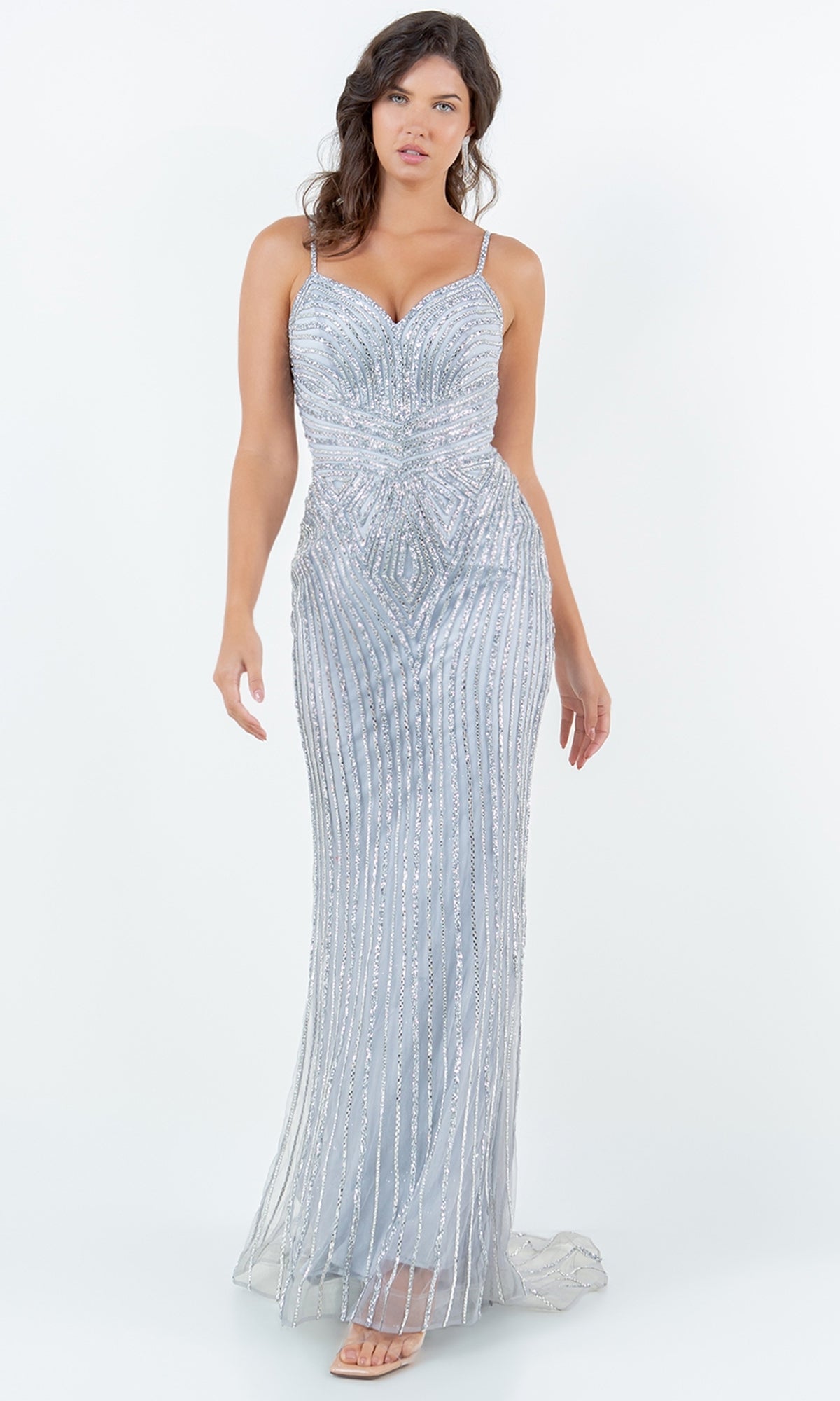 A woman wears the Cinderella Couture 8268J long prom dress, featuring silver sparkly beading and thin straps, standing against a plain white background.